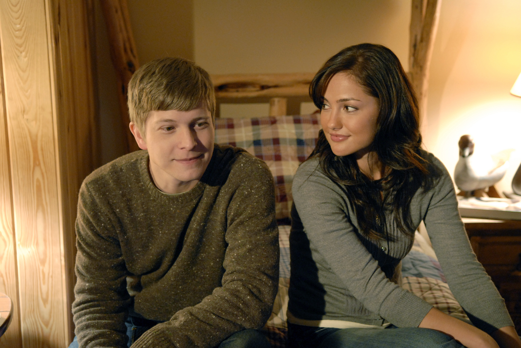 A teenage boy (Matt Czuchry as Chris on "FNL") and girl (Minka Kelly as Lyla) sitting together on a bed.