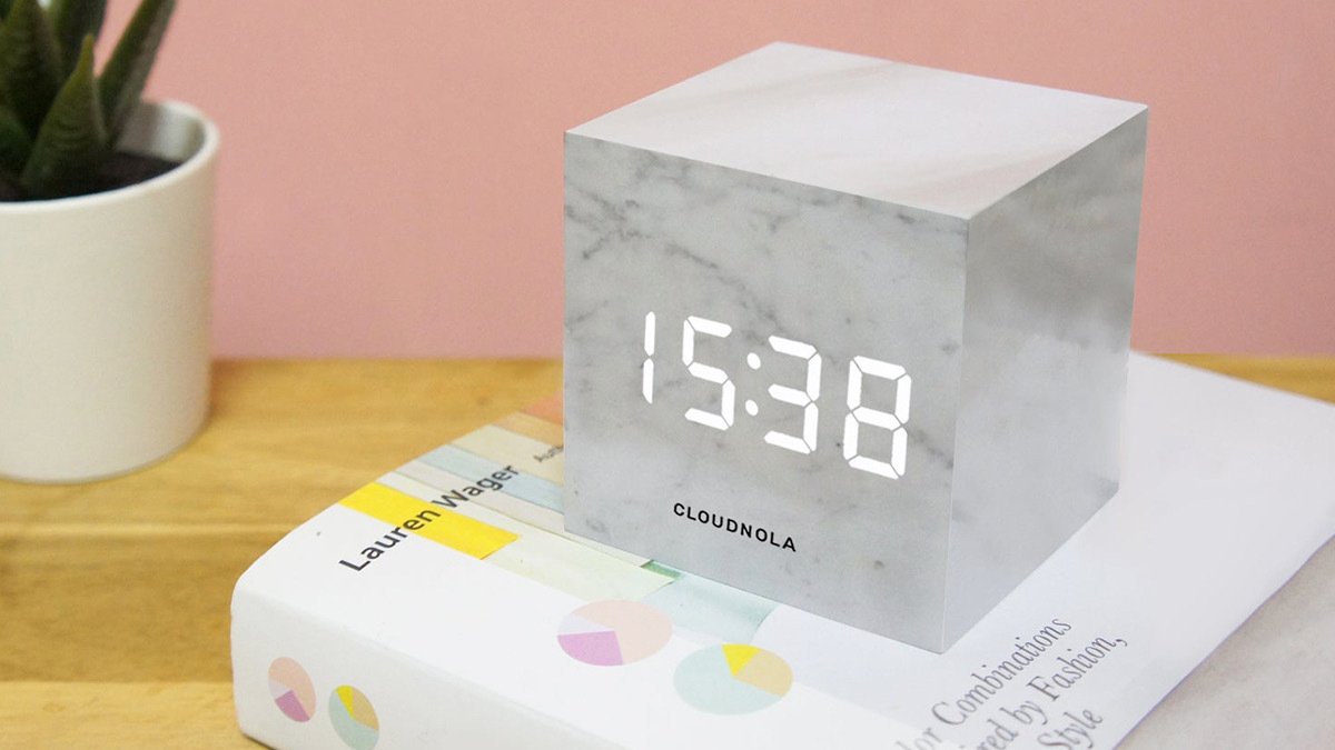 White marble cube showing time on top of book and wooden table
