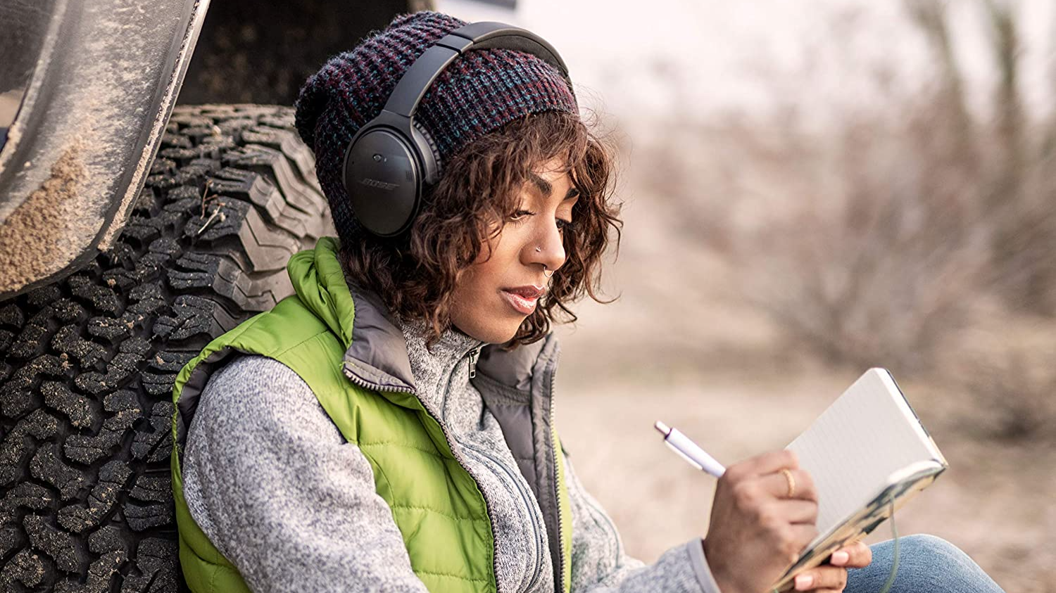 Woman writing in a notebook while listening to headphones