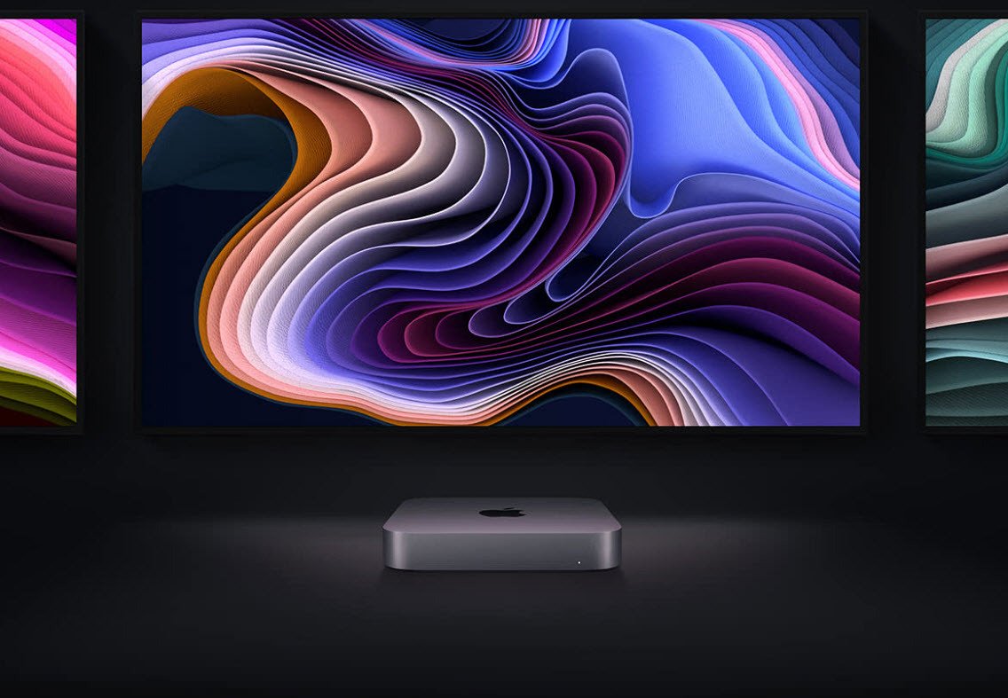 Mac mini M1 2020 desktop in front of Apple monitors with colorful images on display
