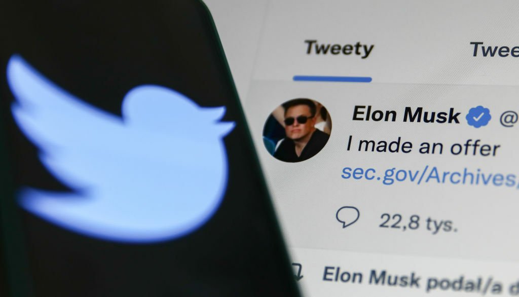 Elon Musk's Tweet displayed on a screen and Twitter logo displayed on a phone screen,