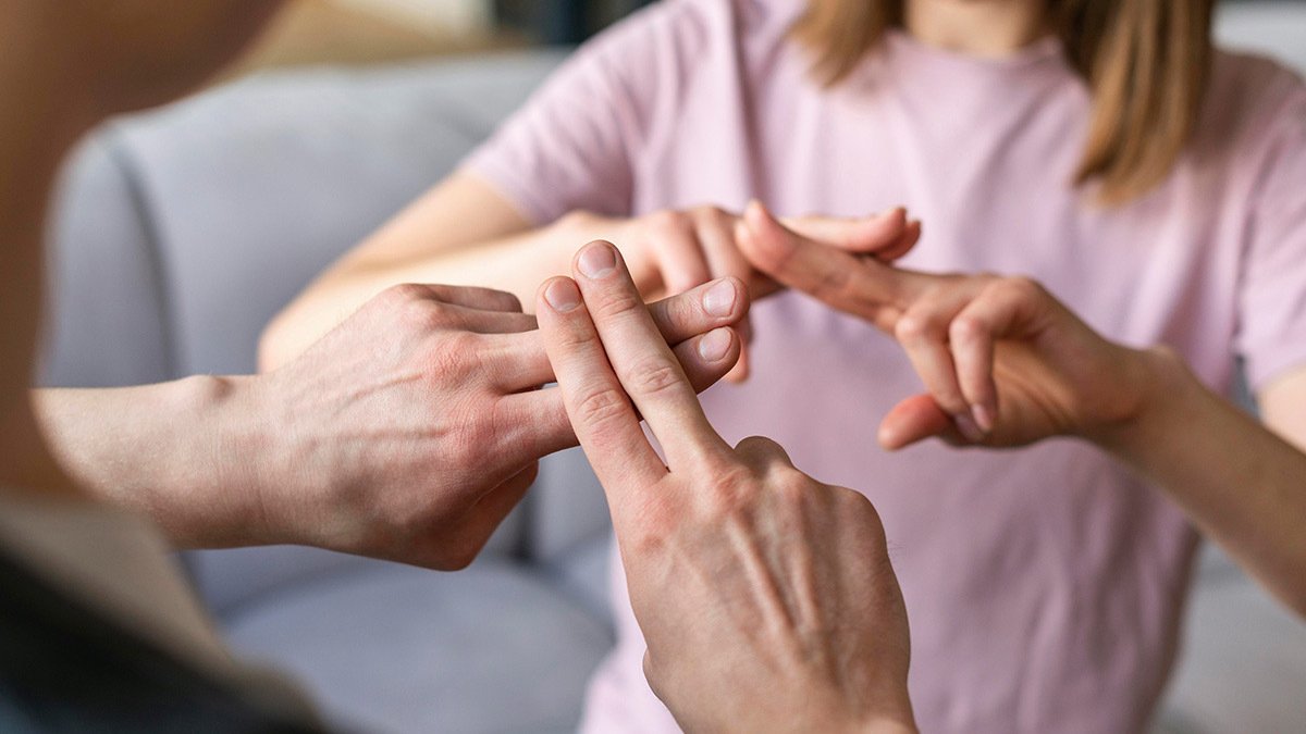 Two pairs of hands doing the same ASL sign