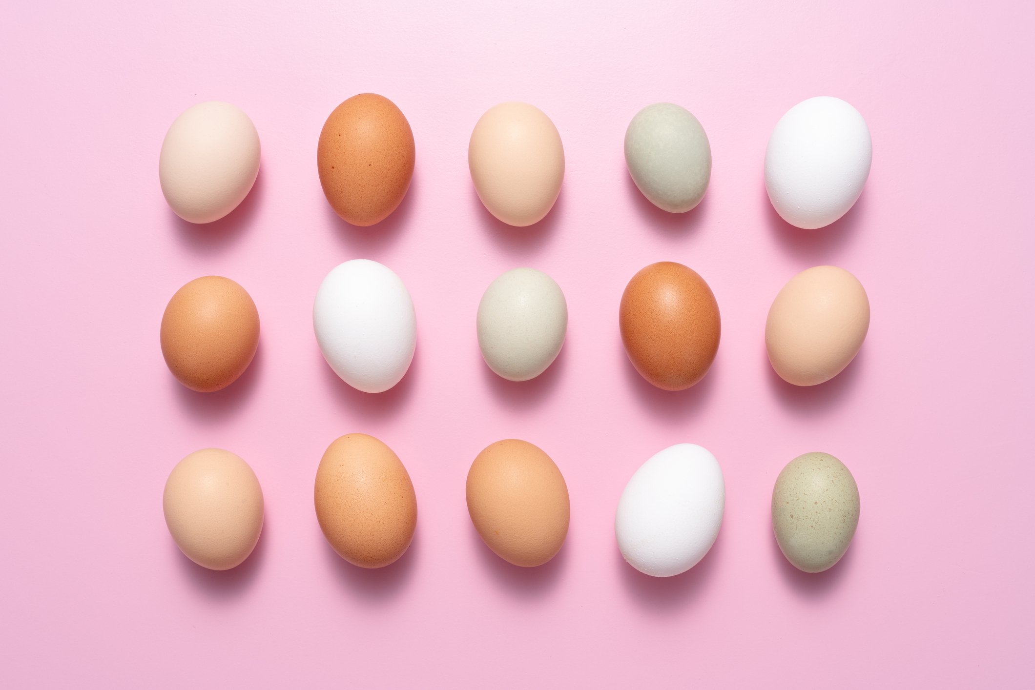 A range of eggs against a bright pink background.