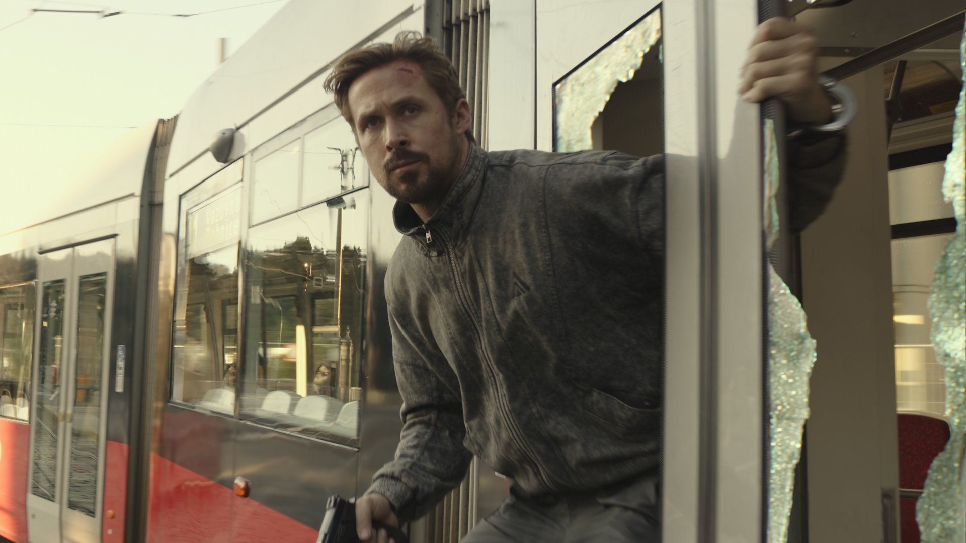 Ryan Gosling hangs out of a moving train holding a gun in the trailer for 