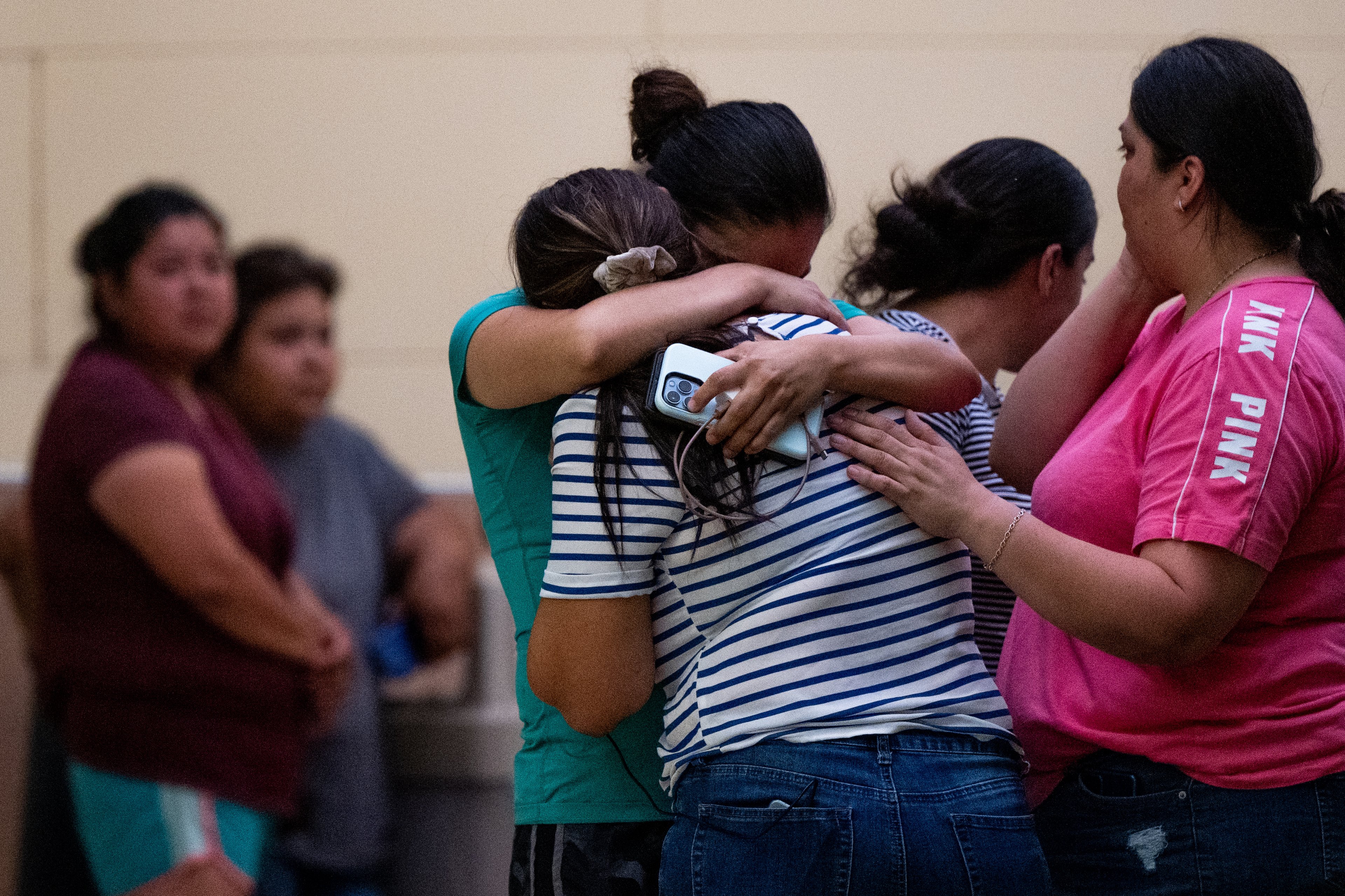 Two women hugging with a crowd around them following a mass shooting in Uvalde, Texas. 
