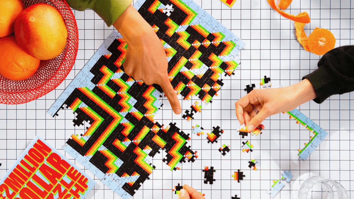 Hands putting together puzzle of QR code with box and oranges beside it