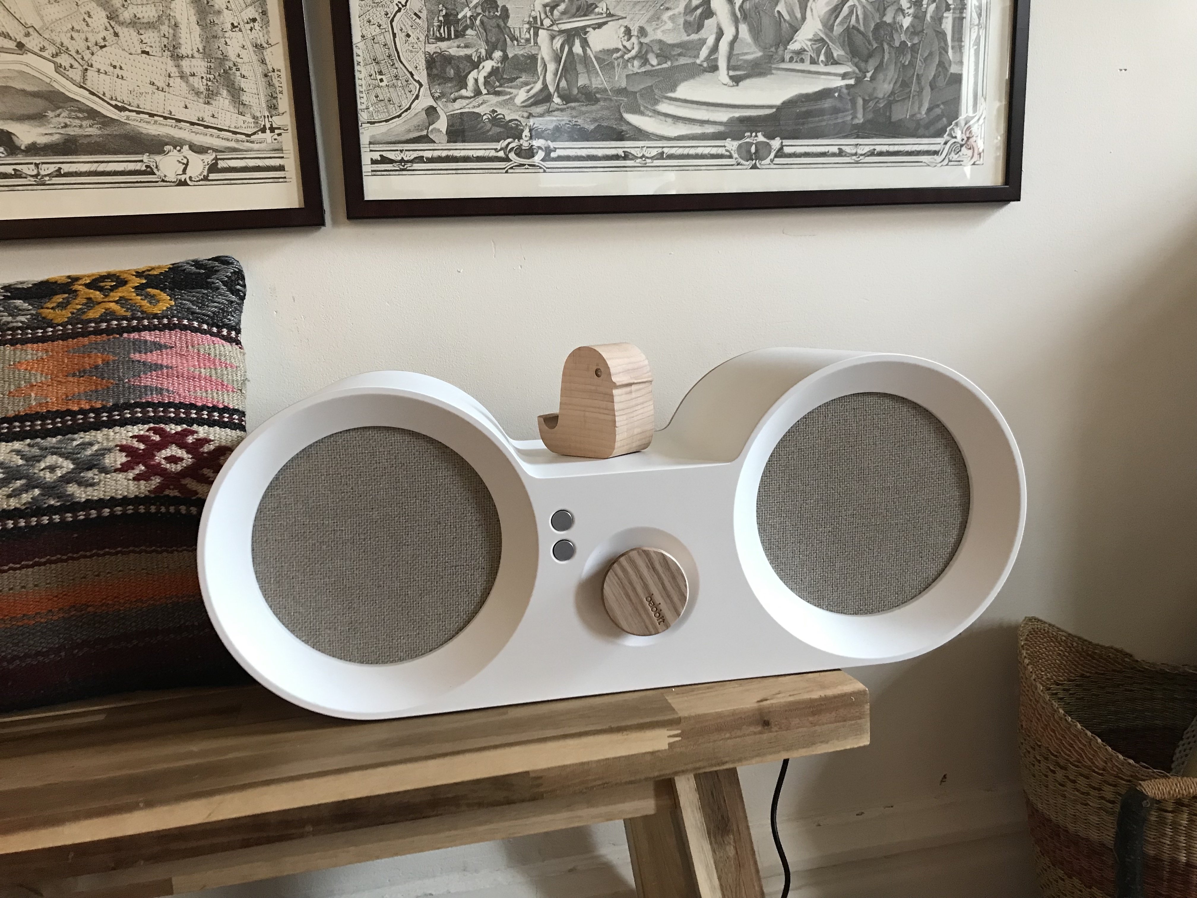 white speaker with rounded ends sitting on a bench