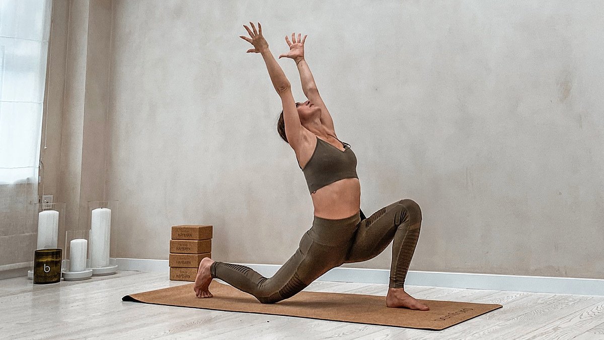 Person on yoga mat lunching and reaching up to the sky