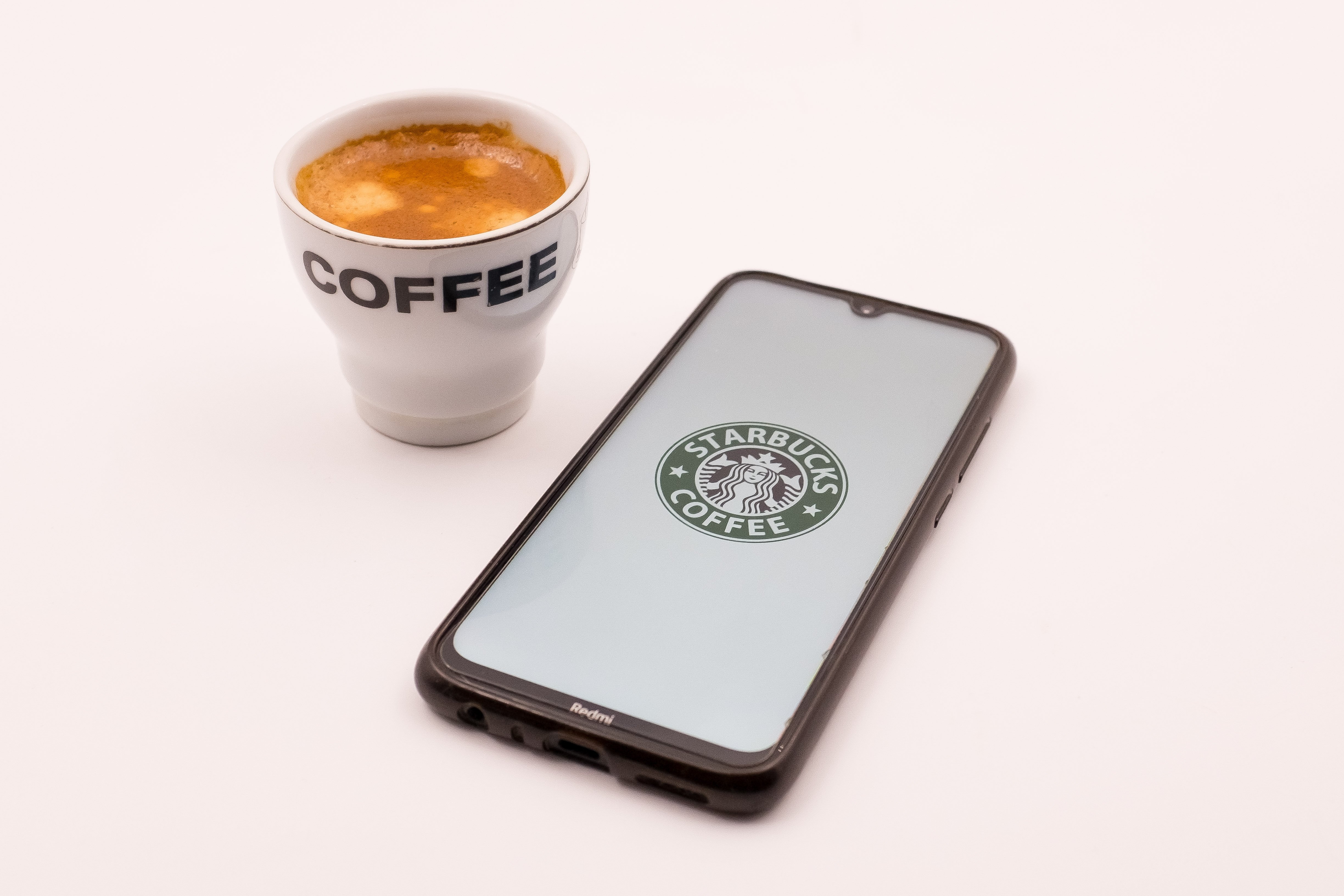 Starbucks logo on an iPhone next to a cup of coffee