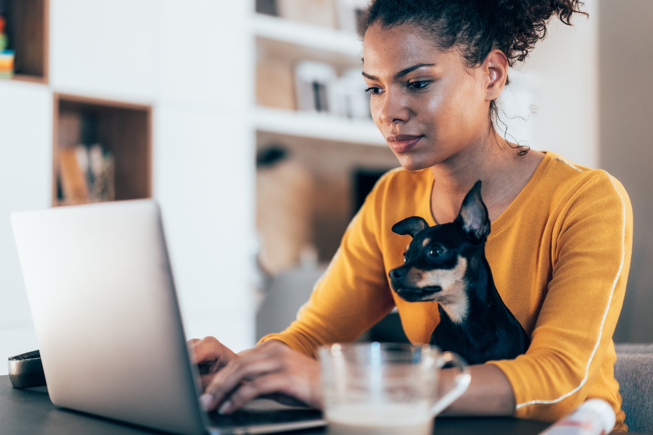 Image of woman with little dog on her lap sitting in front of her laptop