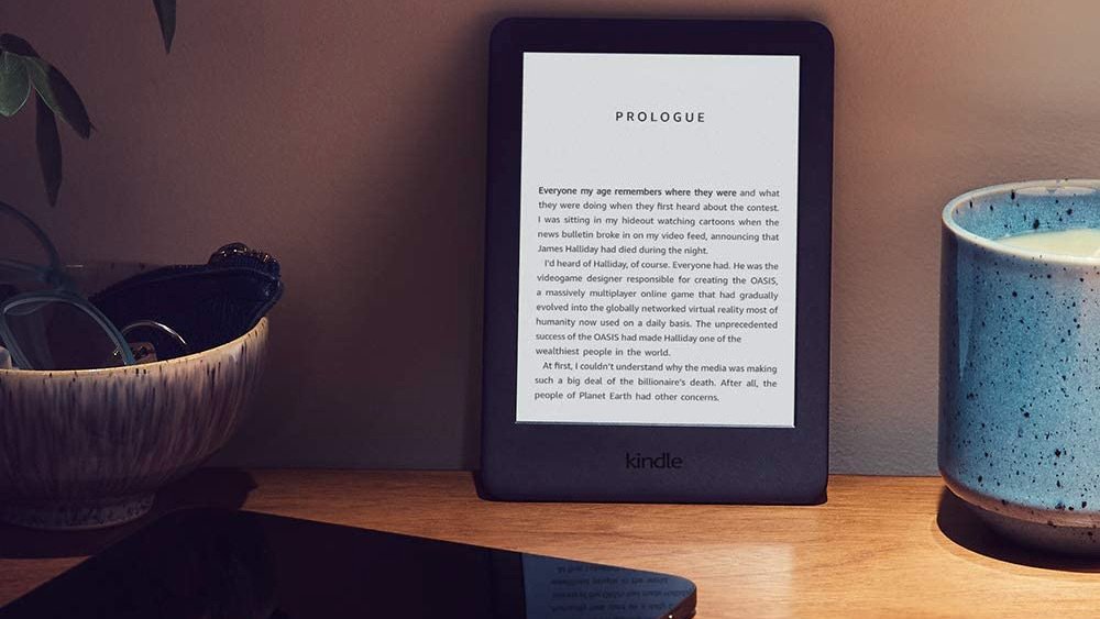 Black kindle with prologue on screen next to bowl and candle on table