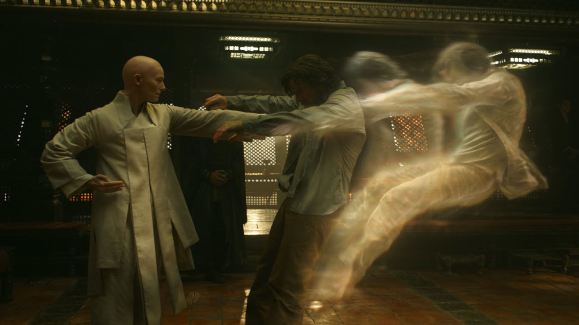 A bald monk (actor Tilda Swinton) punches a disheveled man (actor Benedict Cumberbatch), causing a ghostlike imprint to be ejected from his physical body. Still from "Doctor Strange."