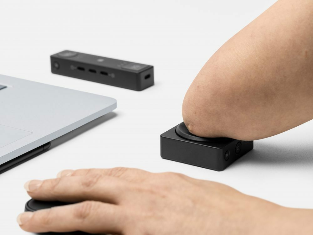 Image of an arm without a hand pressing the button of Microsoft's new adaptive PC accessories