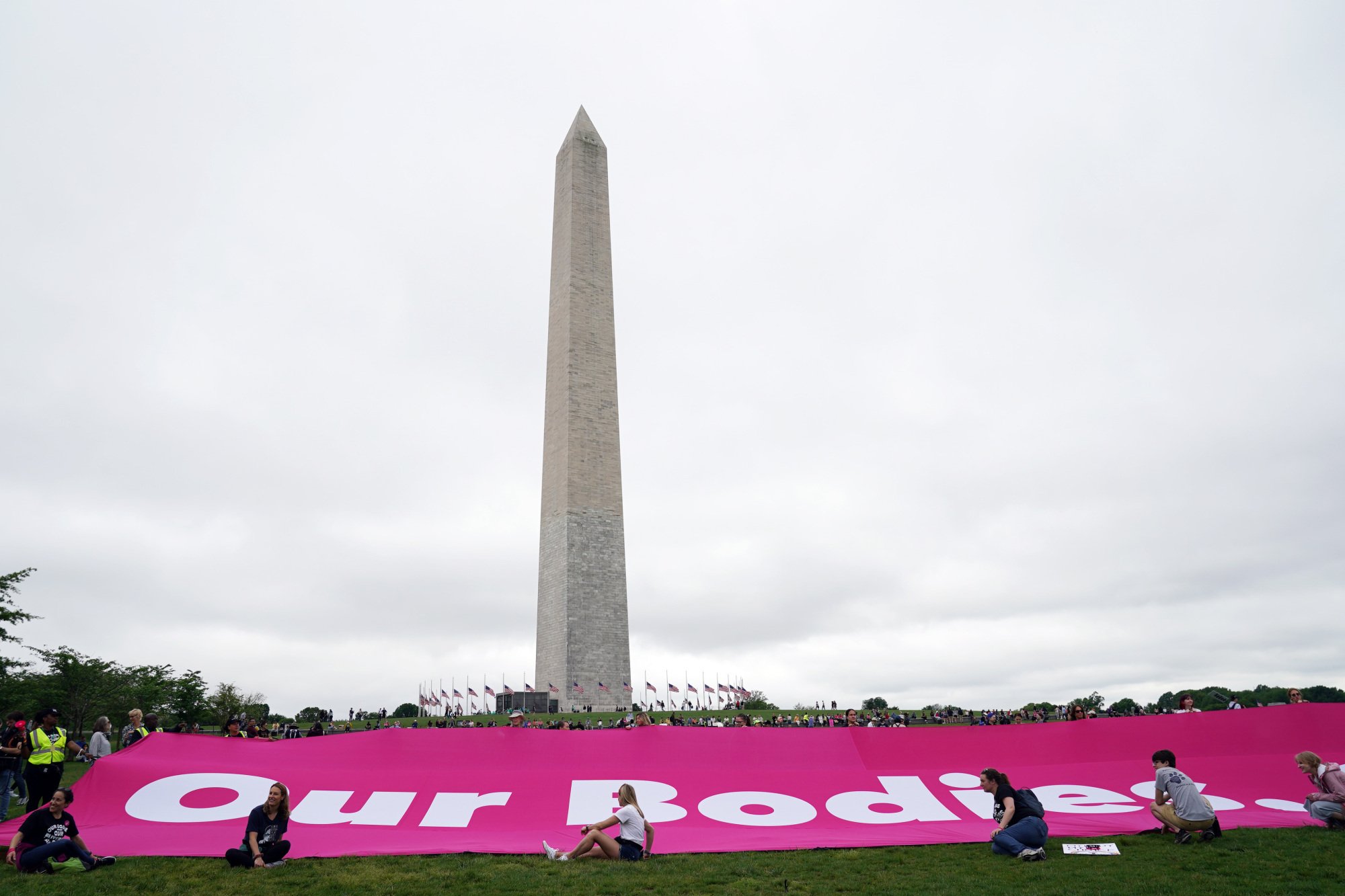A large pink banner reading "Our Bodies" lays out in front of the Washington Monument.