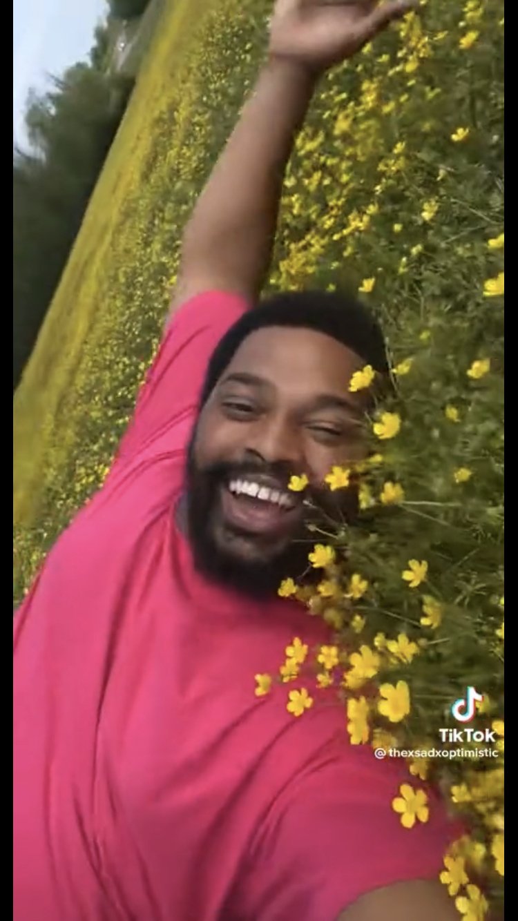 thexsadxoptimistic laying in a green field in a pink shirt