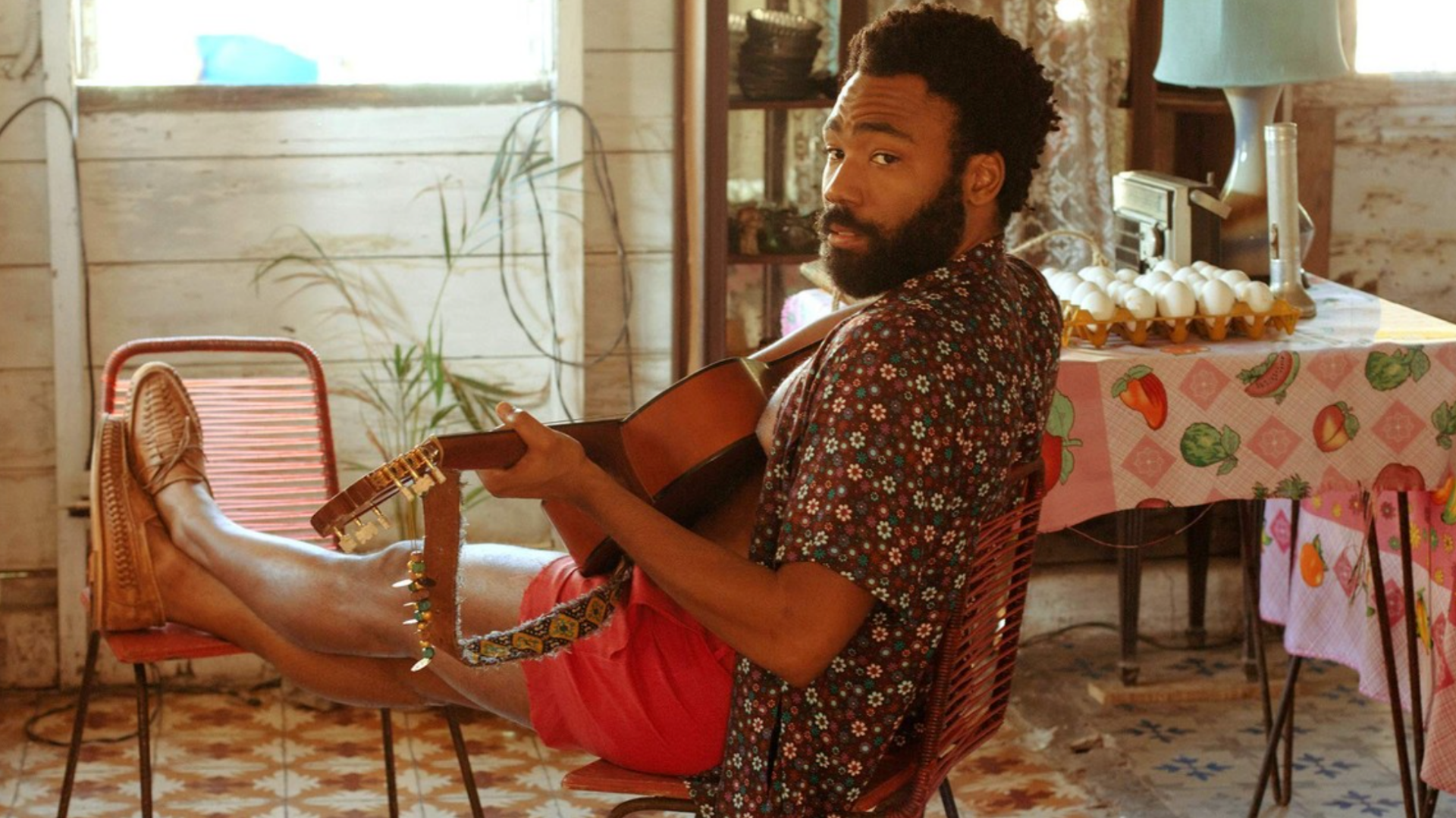 A man in a Hawaiian shirt playing a guitar