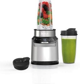 Ninja BN401 Nutri Pro personal blender with fruit next to cup of green smoothie