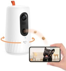 a person holding a smartphone displaying a photo of a dog in front of a eufy pet dog camera