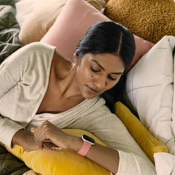 a woman laying in bed while looking at a fitbit on her wrist