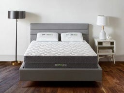 White mattress on grey bed between lamps