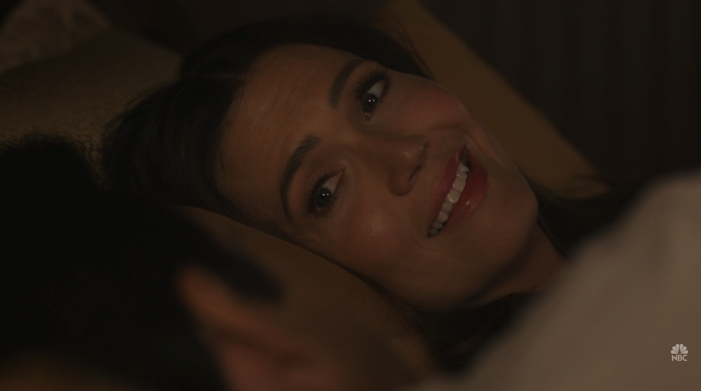 A woman (Mandy Moore) laying in bed looking at a man (Milo Ventimiglia) next to her.