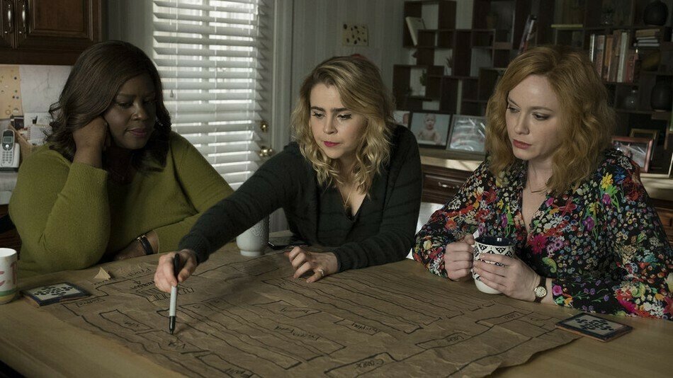 Three women sitting around a table marking on a map.