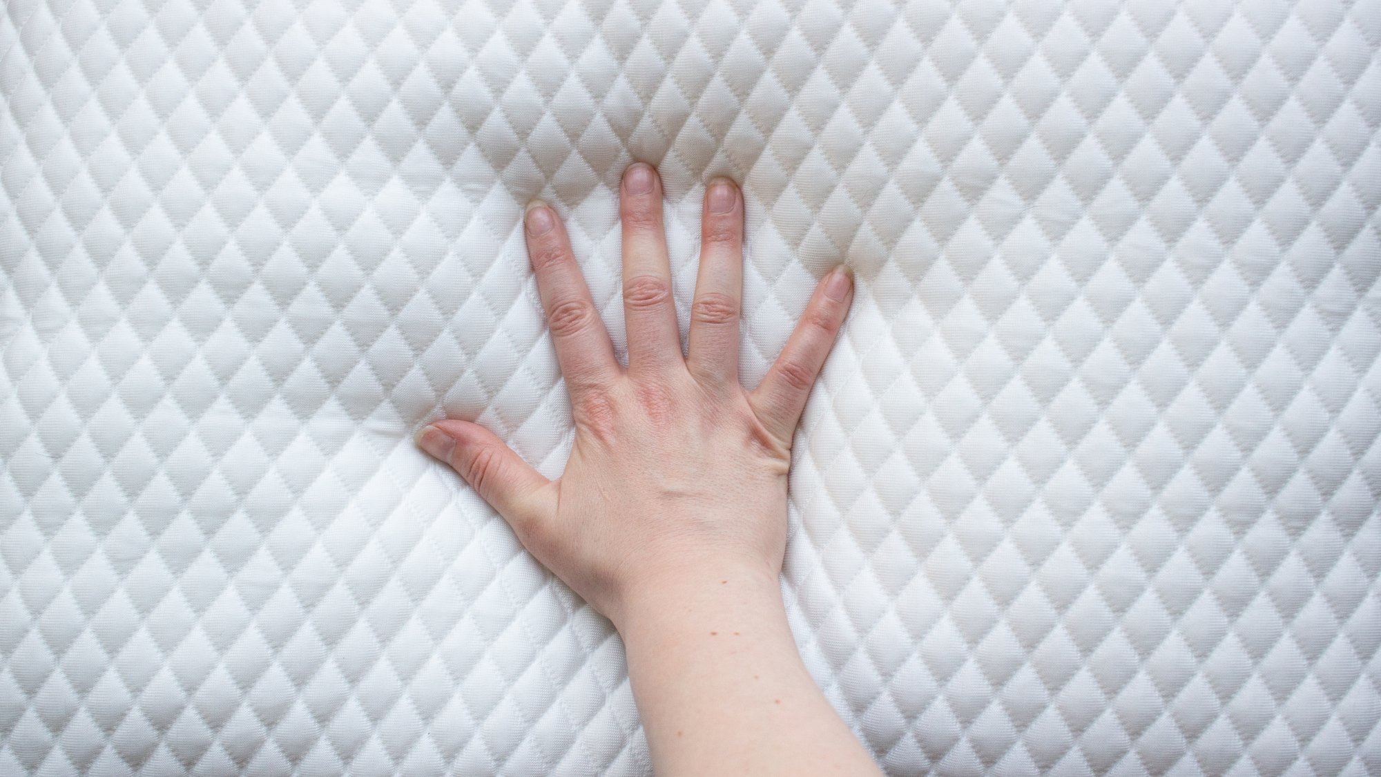 person's hand squishing into a memory foam pillow