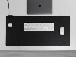 Keyboard and mouse on top of black mat in front of laptop