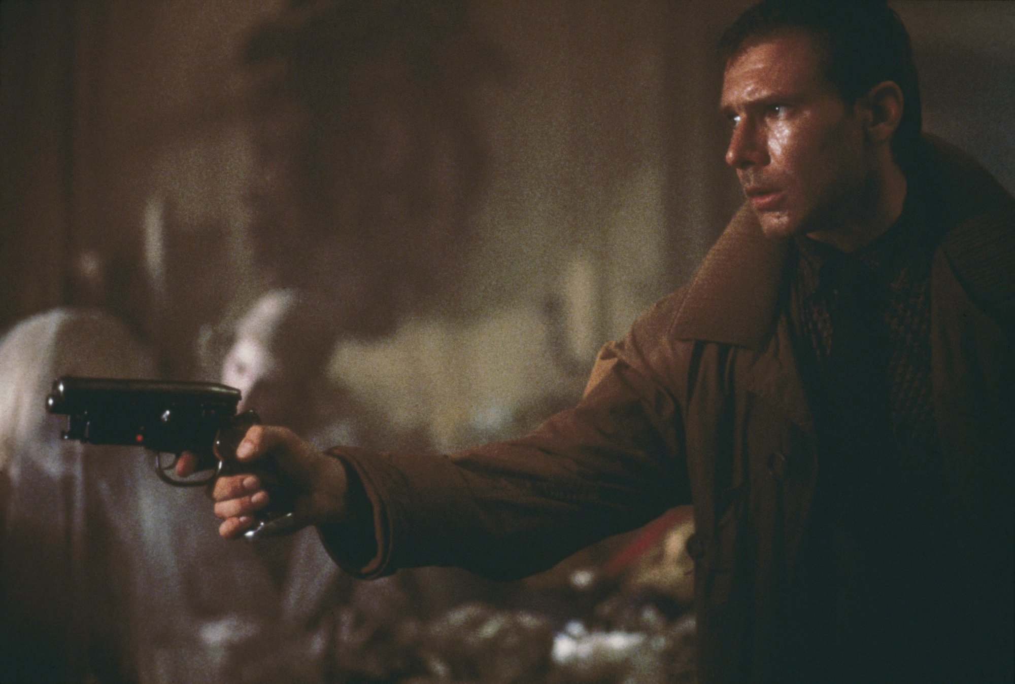 A man in a trenchcoat holding a gun.