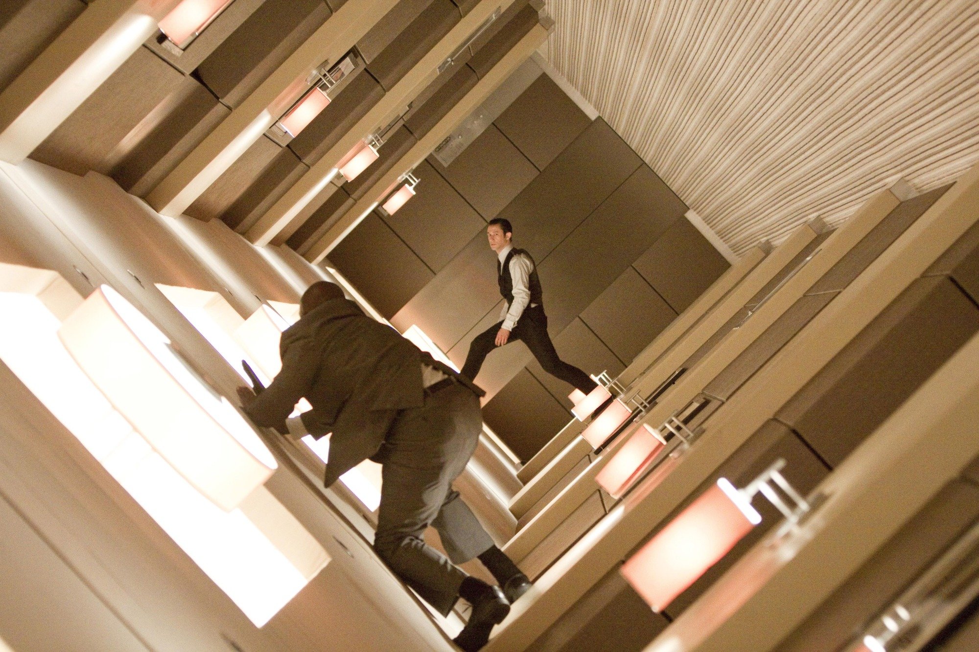 Two men in suits fighting in a rotating hallway.