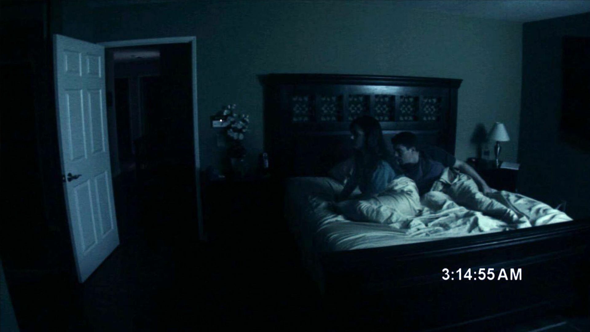A couple in bed, looking spooked.