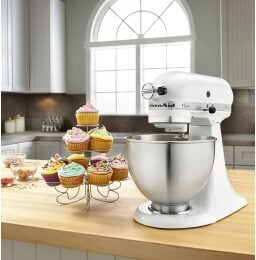 a white kitchenaid stand mixer next to a tower of cupcakes