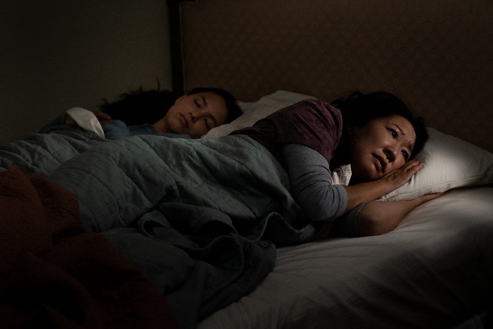 A teen daughter slumbers next to her awake and worried mother.