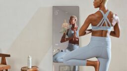 a woman wearing a blue workout set doing yoga in front of a mirror smart home gym