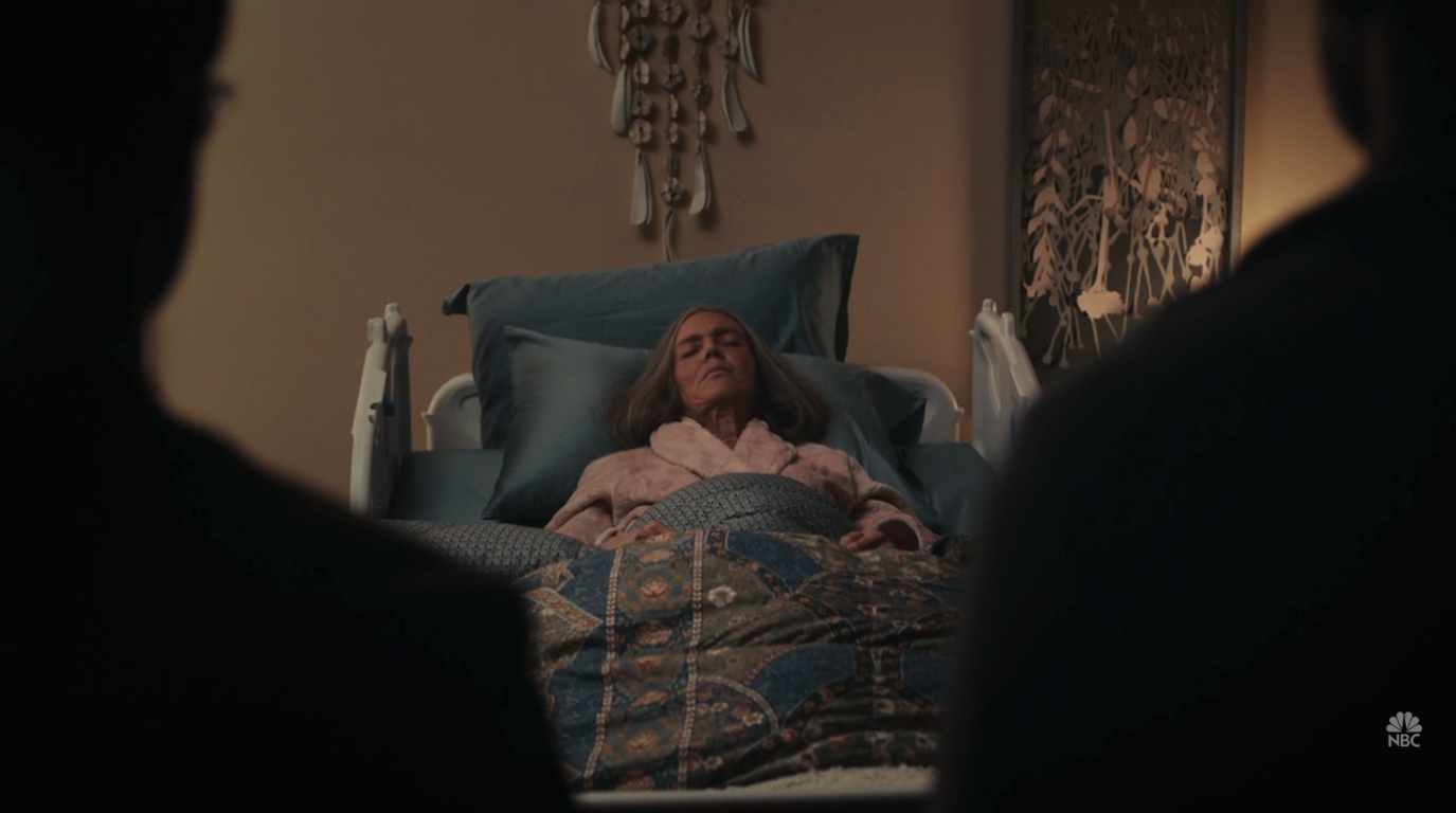 Two men standing in front of an elderly woman who's lying in bed.