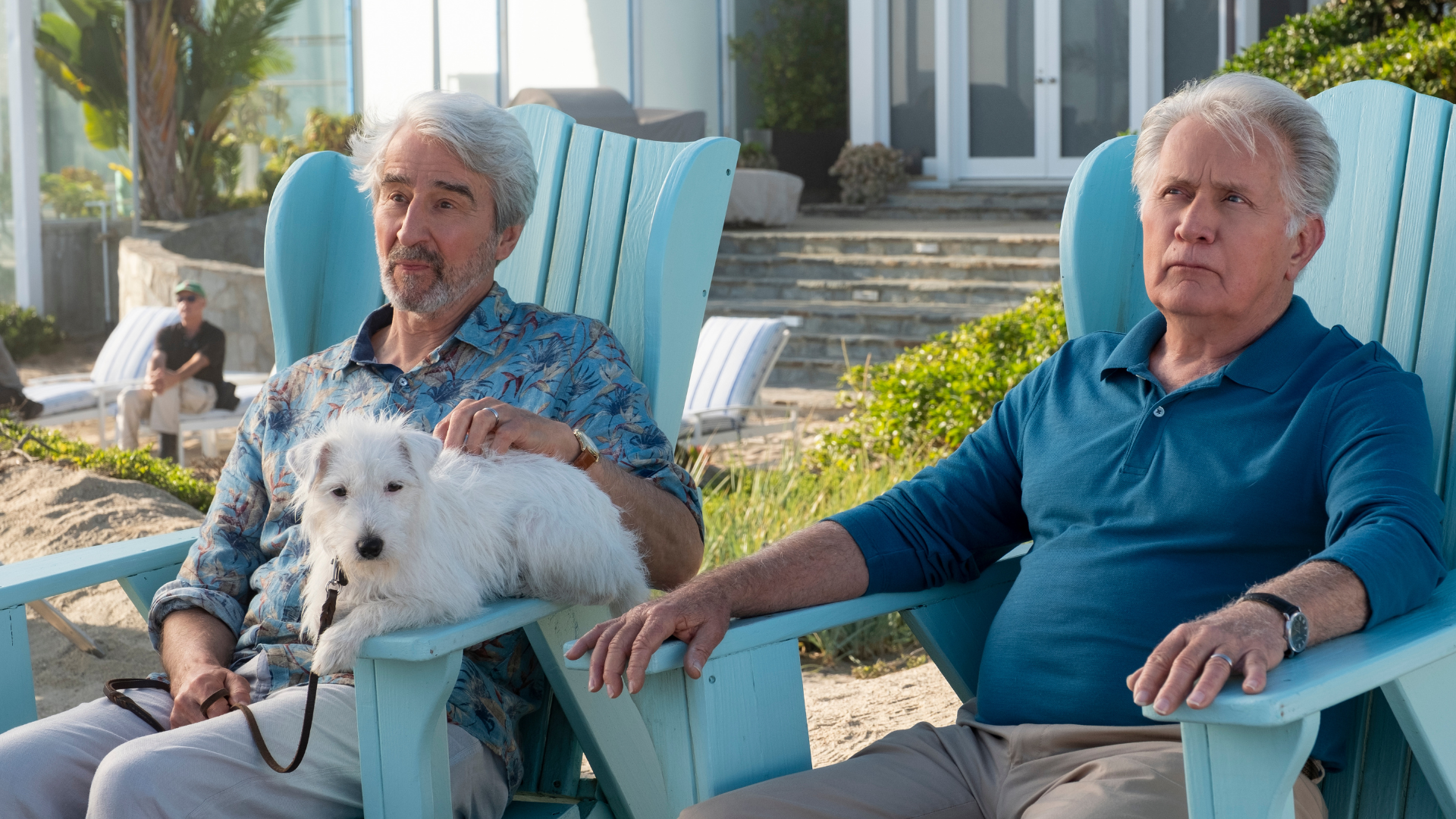 Two elderly men relax in Adirondack chairs.