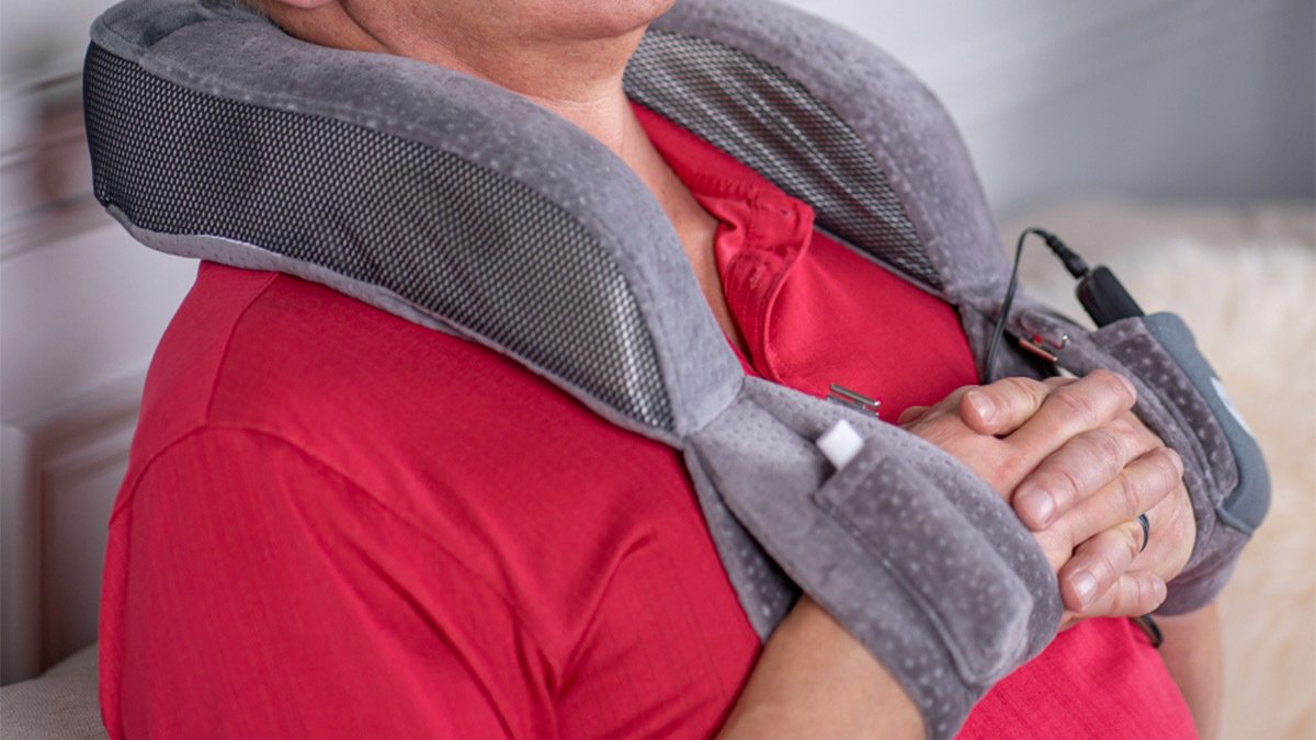 Body of person in red wearing grey neck massager with wrist loops