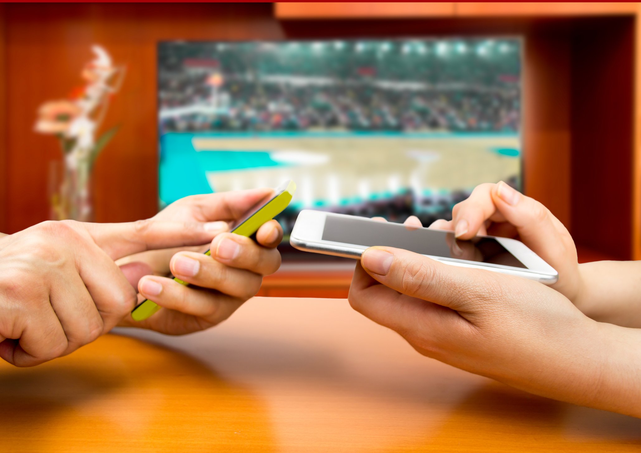 Two smartphones in front of TV with basketball on it