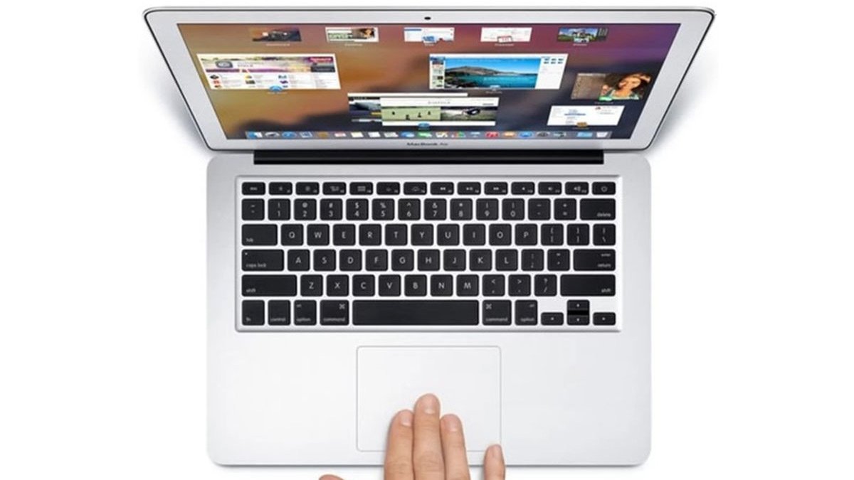 Hand on trackpad of silver laptop with windows open