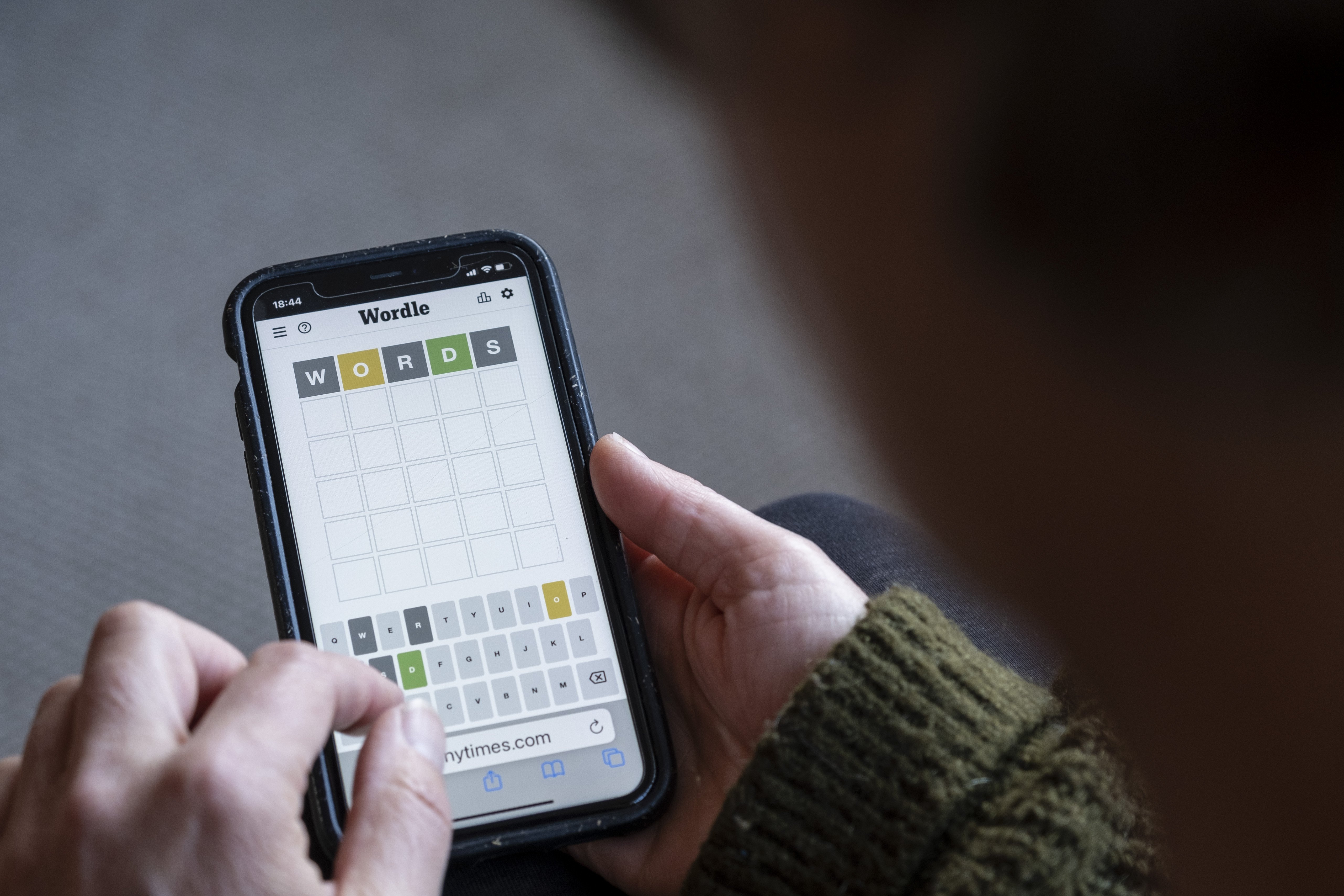 Woman plays Wordle on her smartphone from the living room of her home in this close-up of the game.