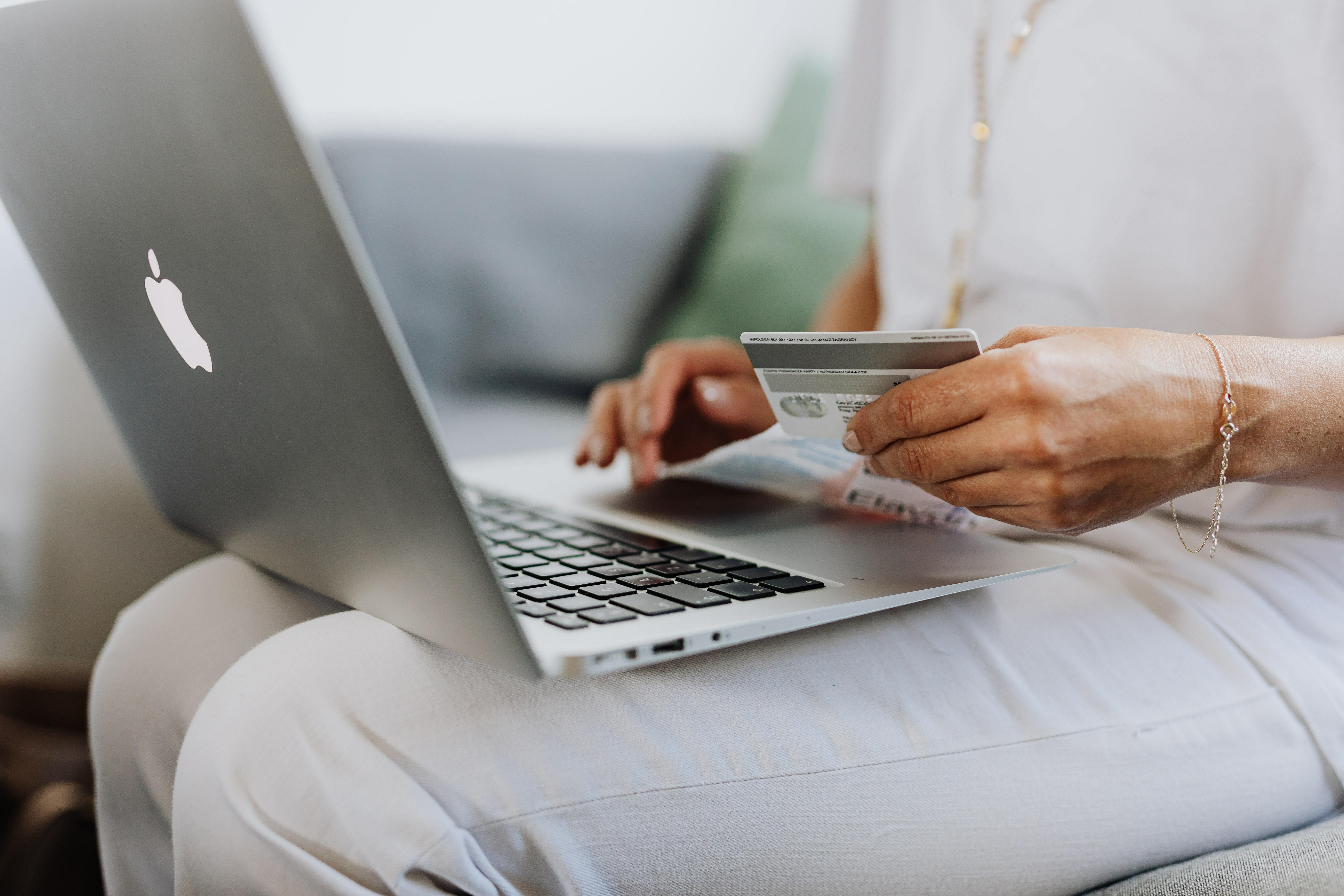 woman with a laptop in her lap and holding a credit card, shopping online