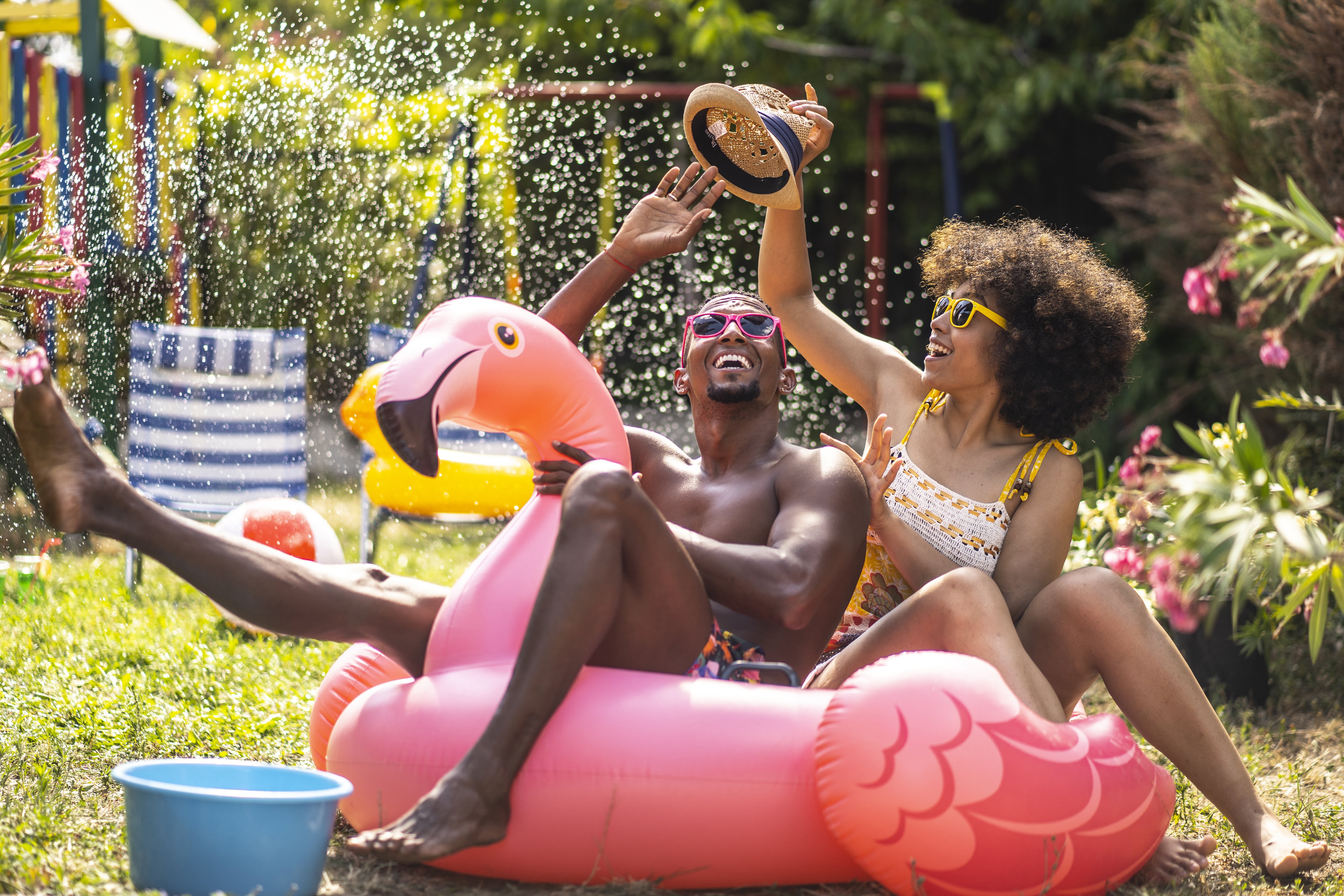 Man and woman relax and laugh in an inflatable flamingo pool