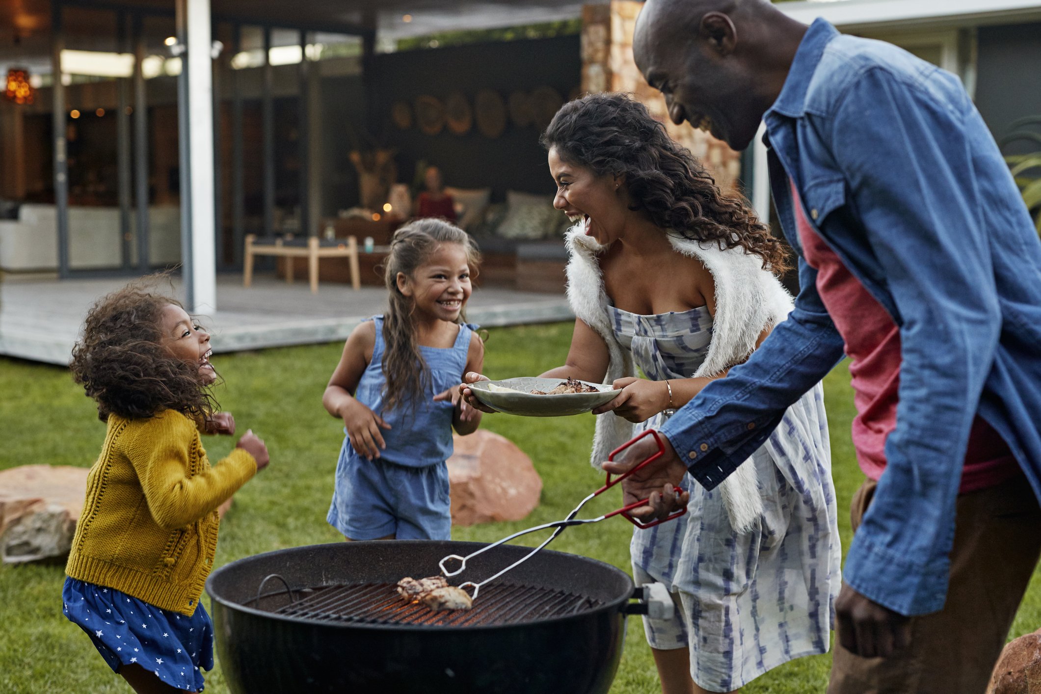 Family of 4 enjoying grilling outside their home