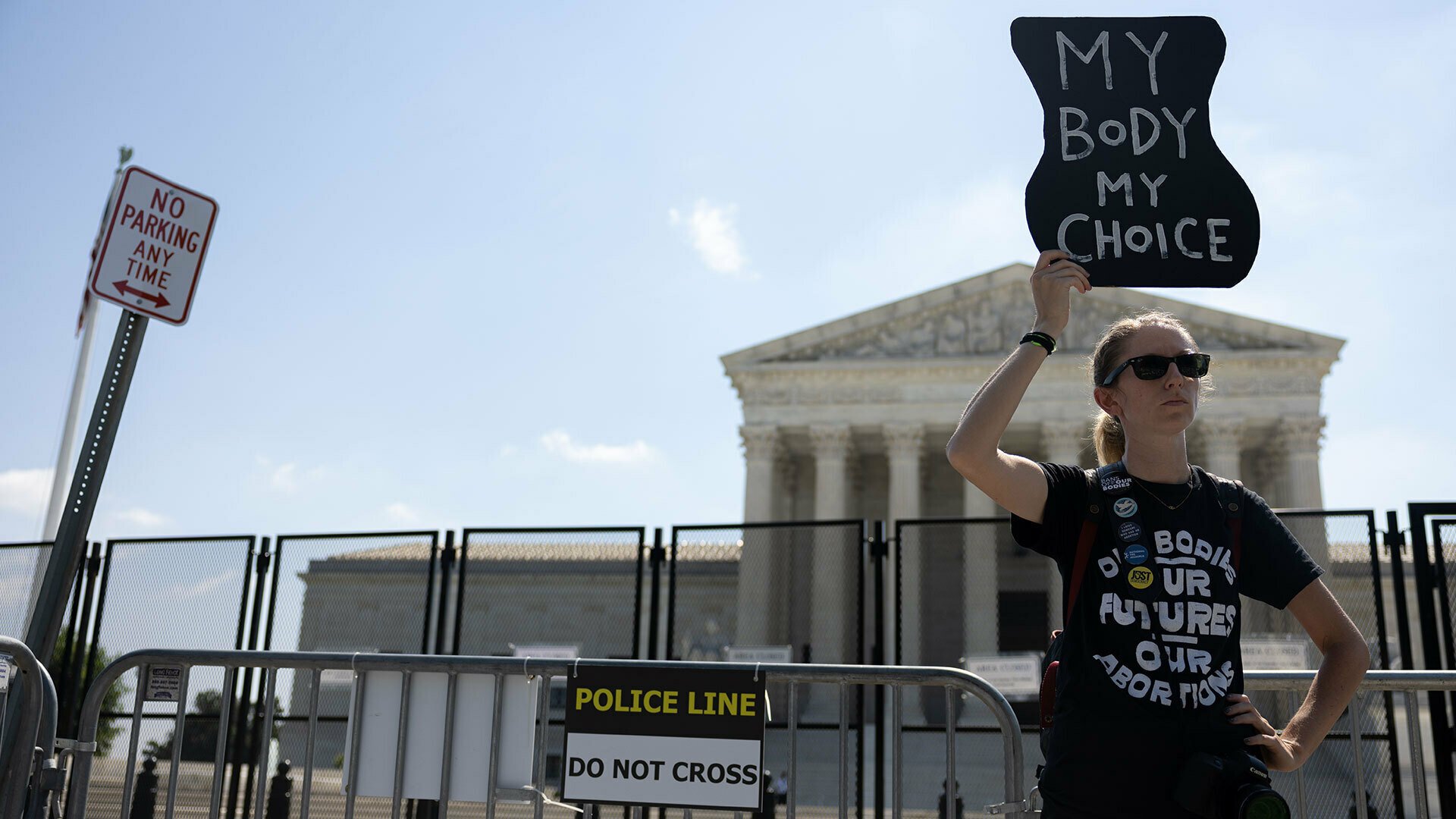 A pro-abortion rights protester stands in front of the Supreme Court holding a sign that reads, 