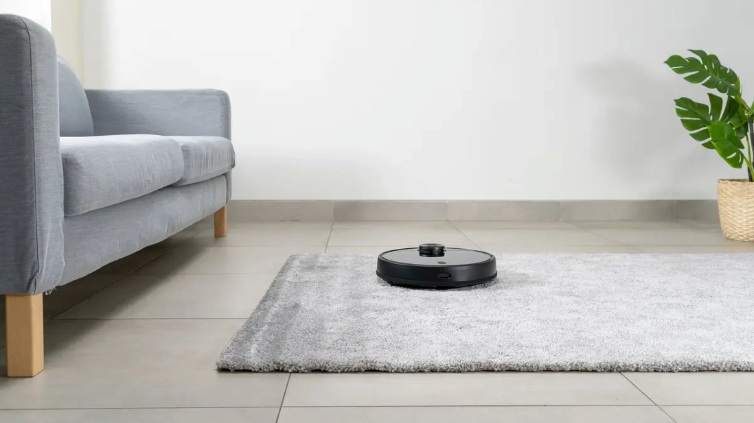 robot vacuum running on gray rug in a living room