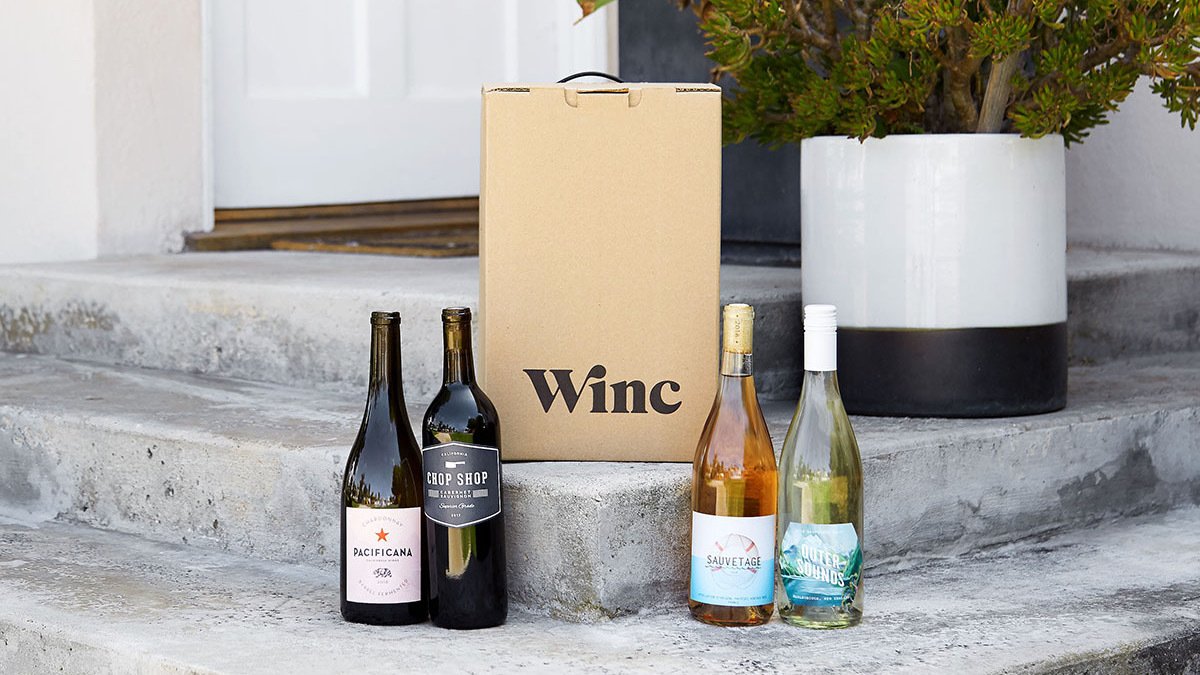 Four bottles of wine on doorstep in front of brown paper bag