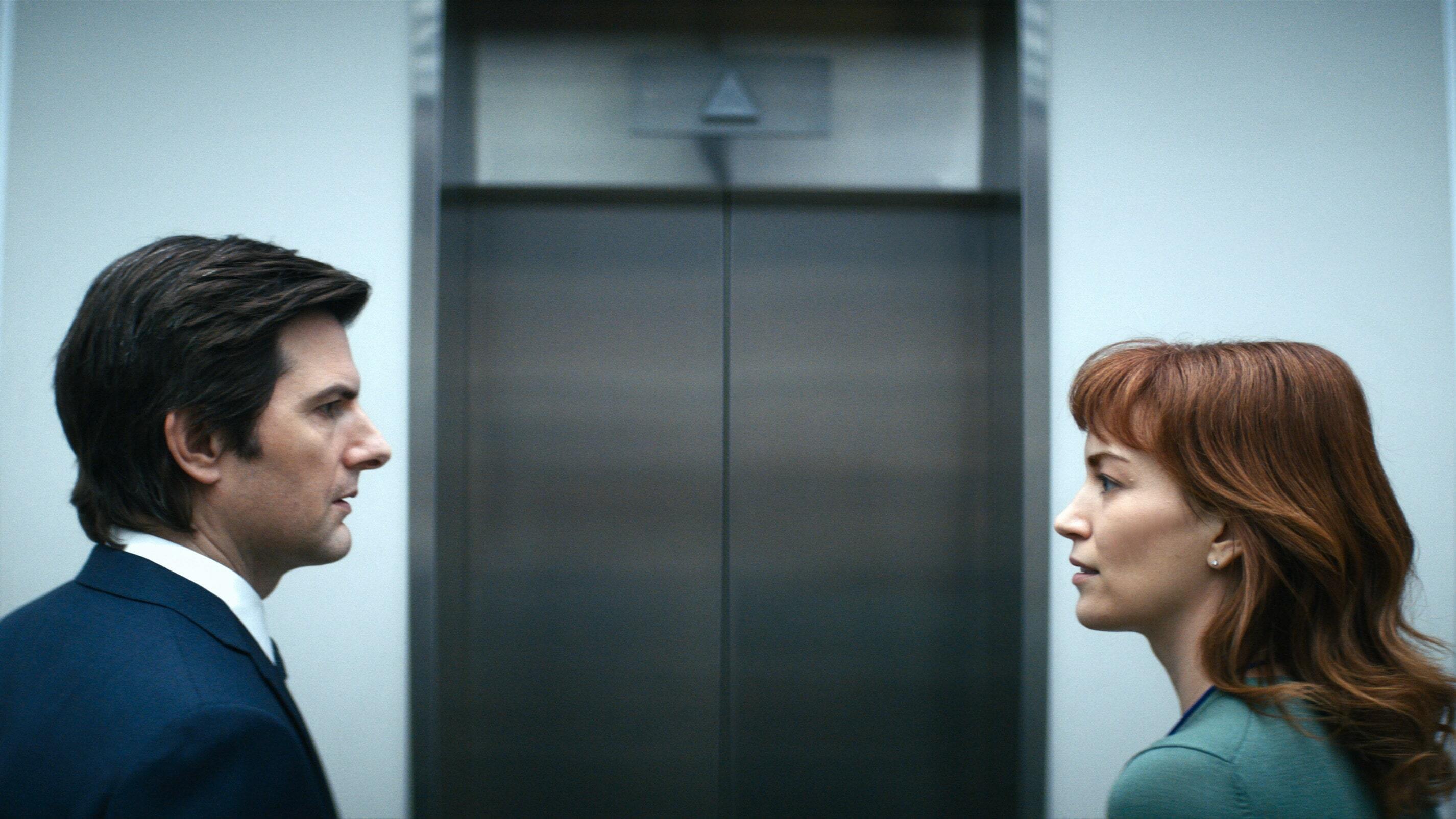 A man and a woman facing each other in front of an elevator.