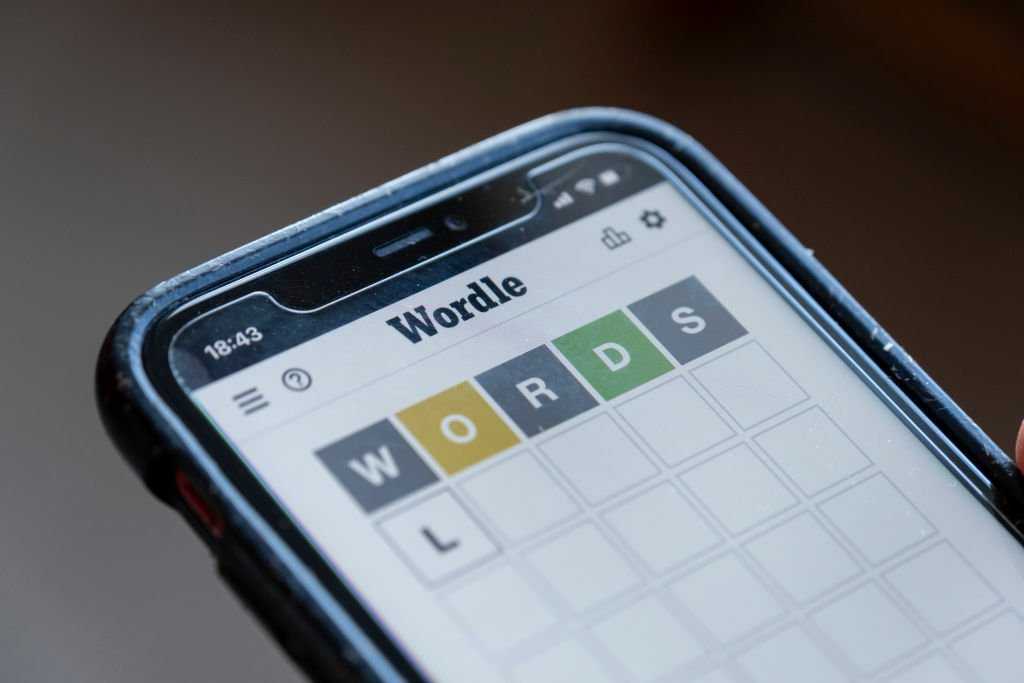 Woman plays Wordle on her smartphone from the living room of her home.