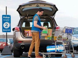 Person loading groceries into car trunk from shopping cart