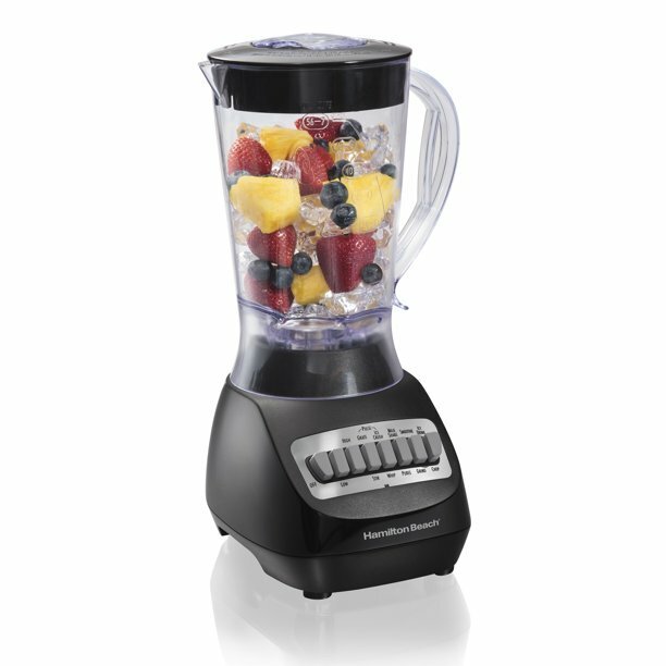 Electric blender with frozen ice, pineapple chunks, strawberries, and blueberries to make into a smoothie